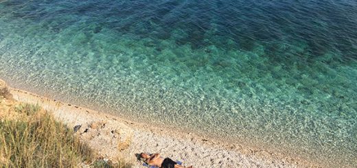homem dormindo em praia deserta com águas cristalinas em hvar, na croácia